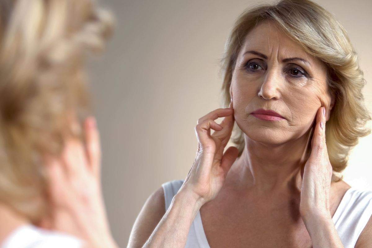 Donna guarda la pelle cadente