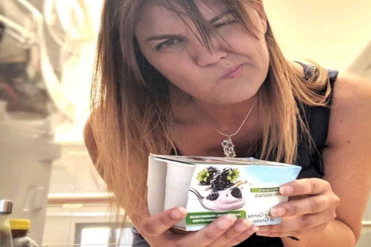 Donna storce le labbra davanti a un barattolo di yogurt