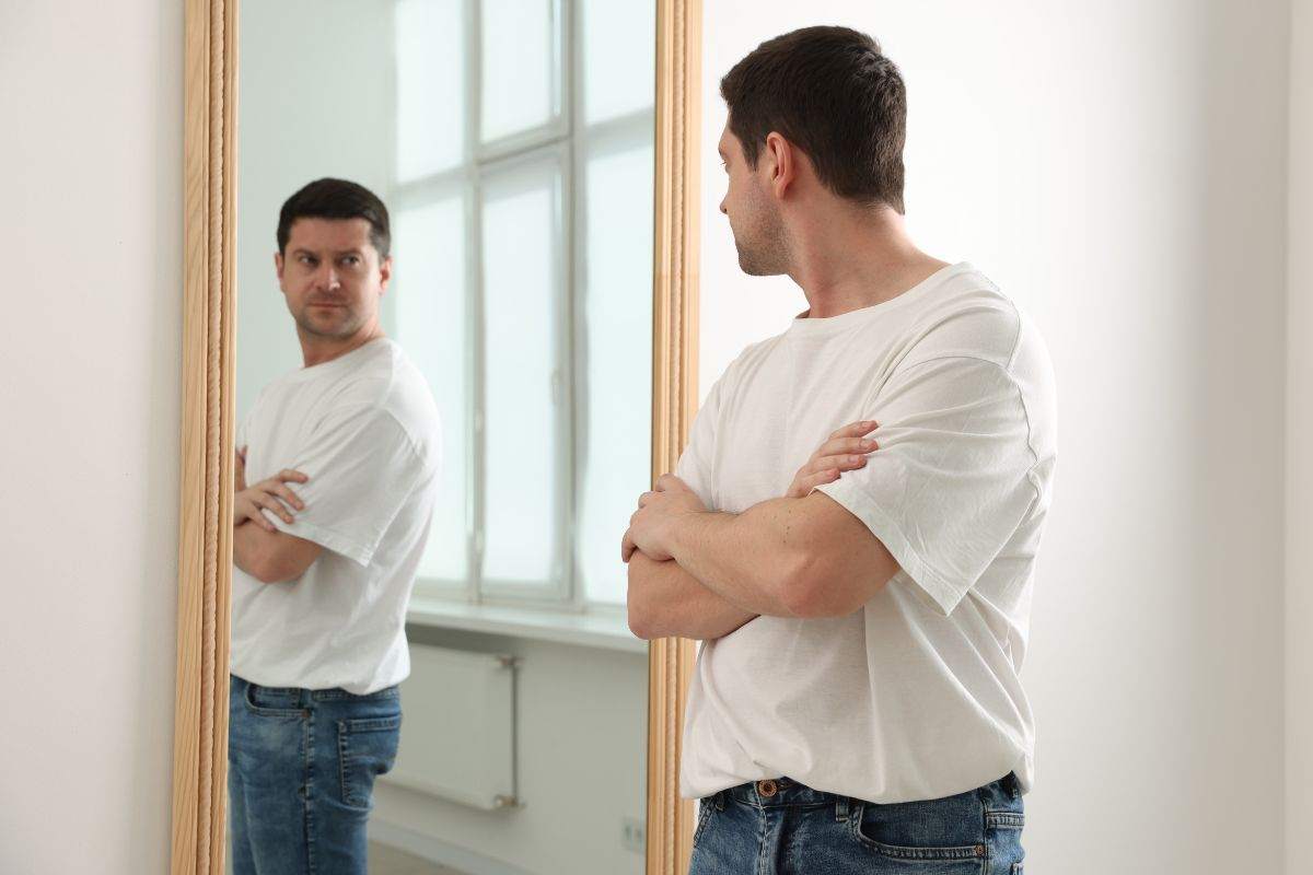 Uomo si guarda perplesso allo specchio