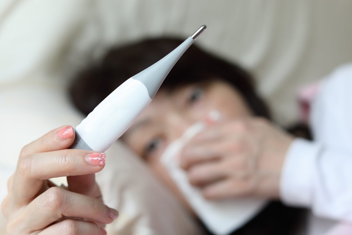 donna a letto con termometro in mano